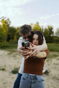 Young couple practicing gun safety outdoors, focusing on firearm handling and training.